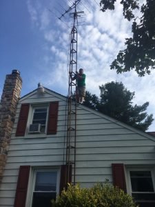 An old tv radial antenna that a friend standing on the roof is about to push over