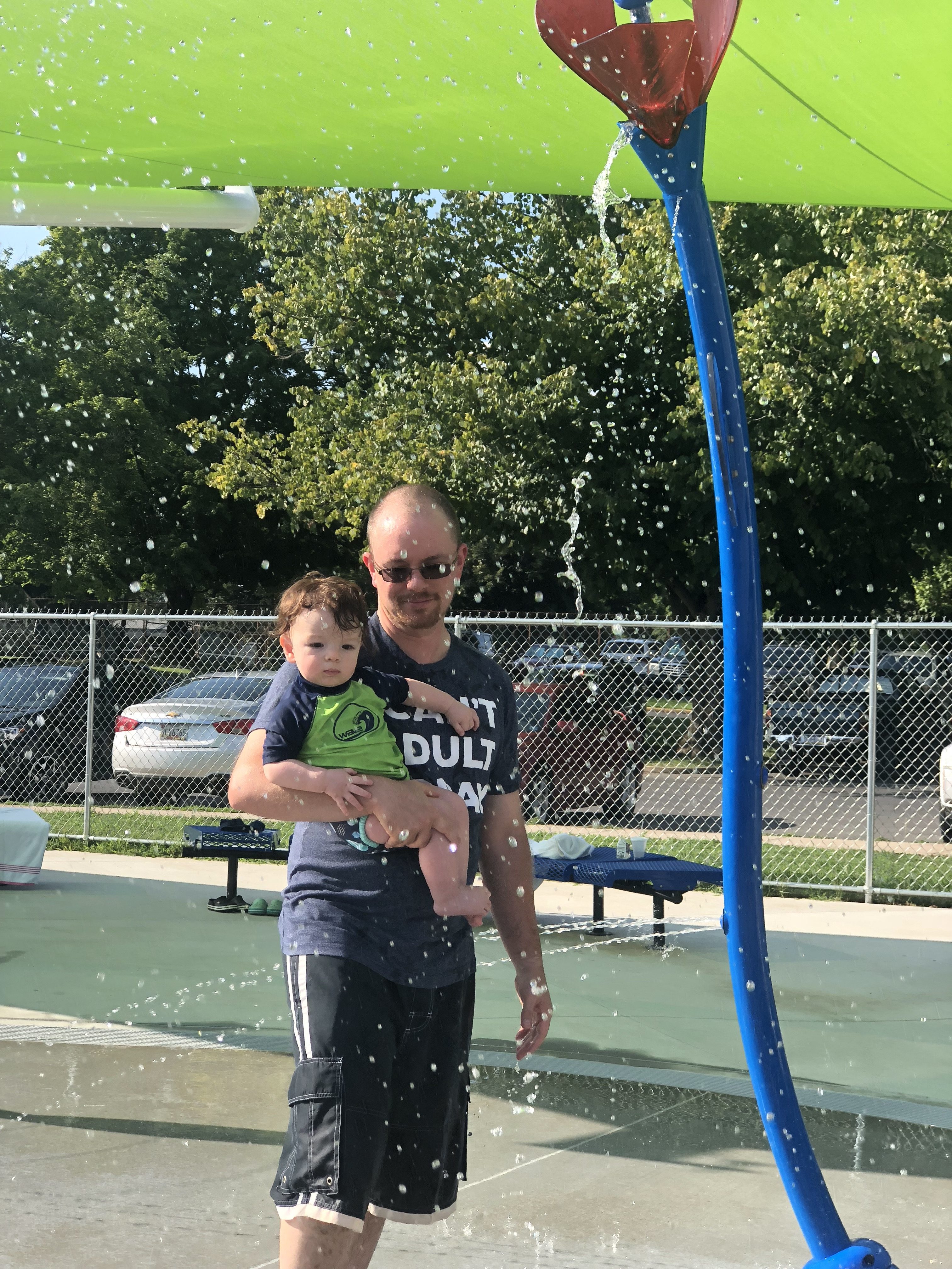 Matt holding Shiloh under a flower sprinkler