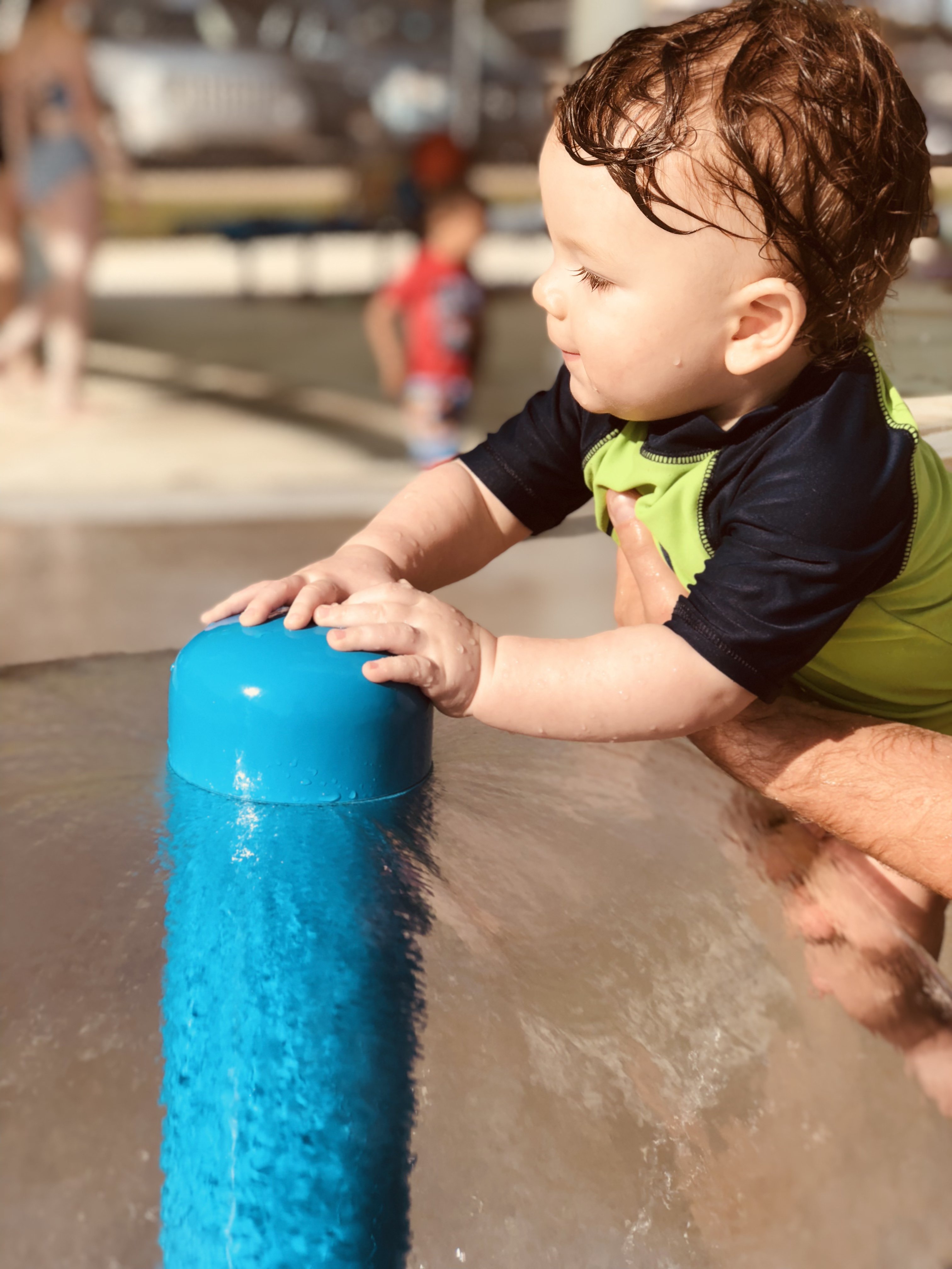9 month old Shiloh running his hands in the umbrella sprinkler waterfall