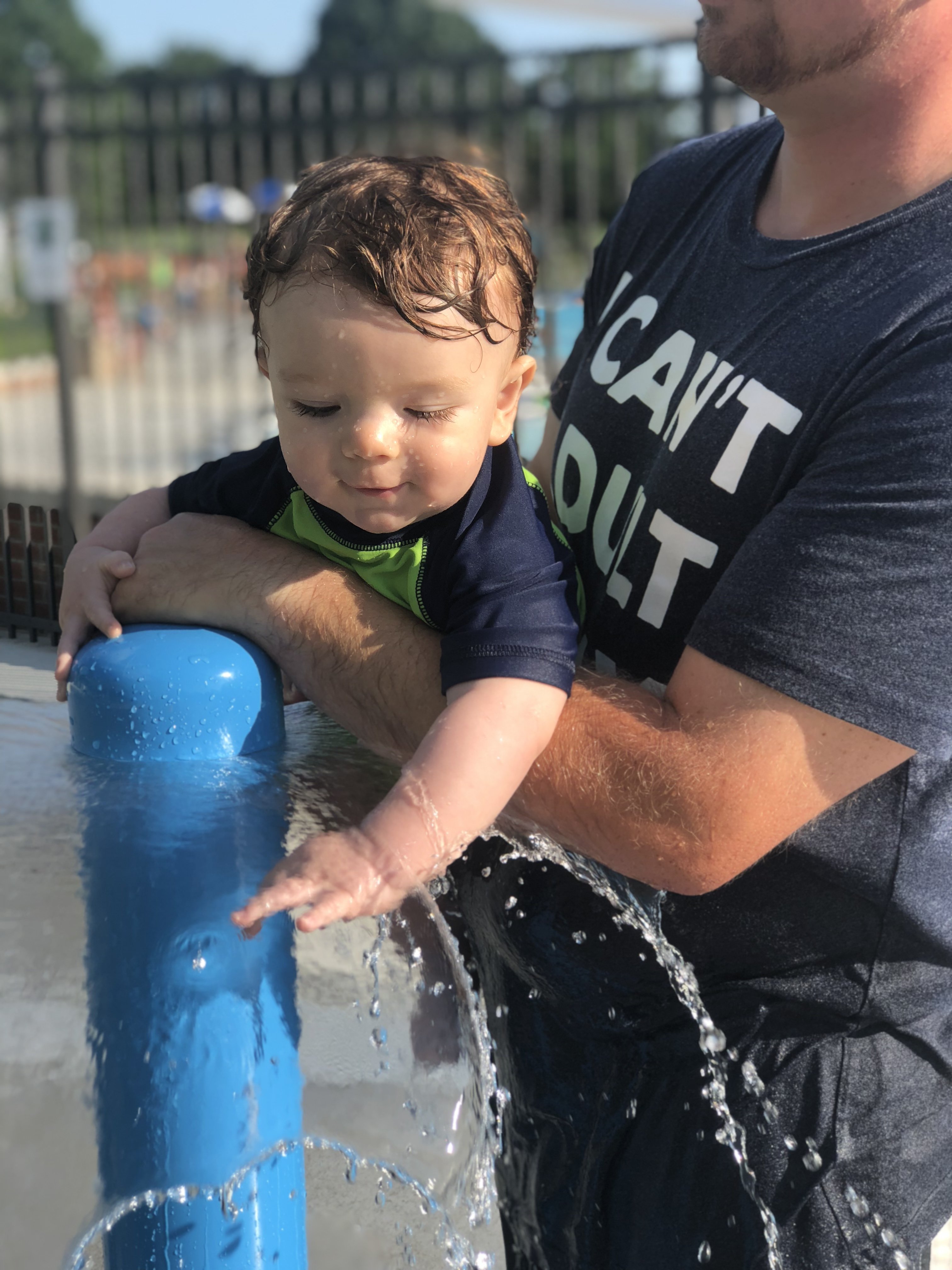 9 month old Shiloh running his hands in the umbrella sprinkler waterfall