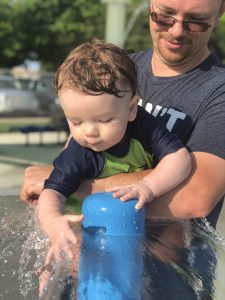 9 month old Shiloh running his hands in the umbrella sprinkler waterfall