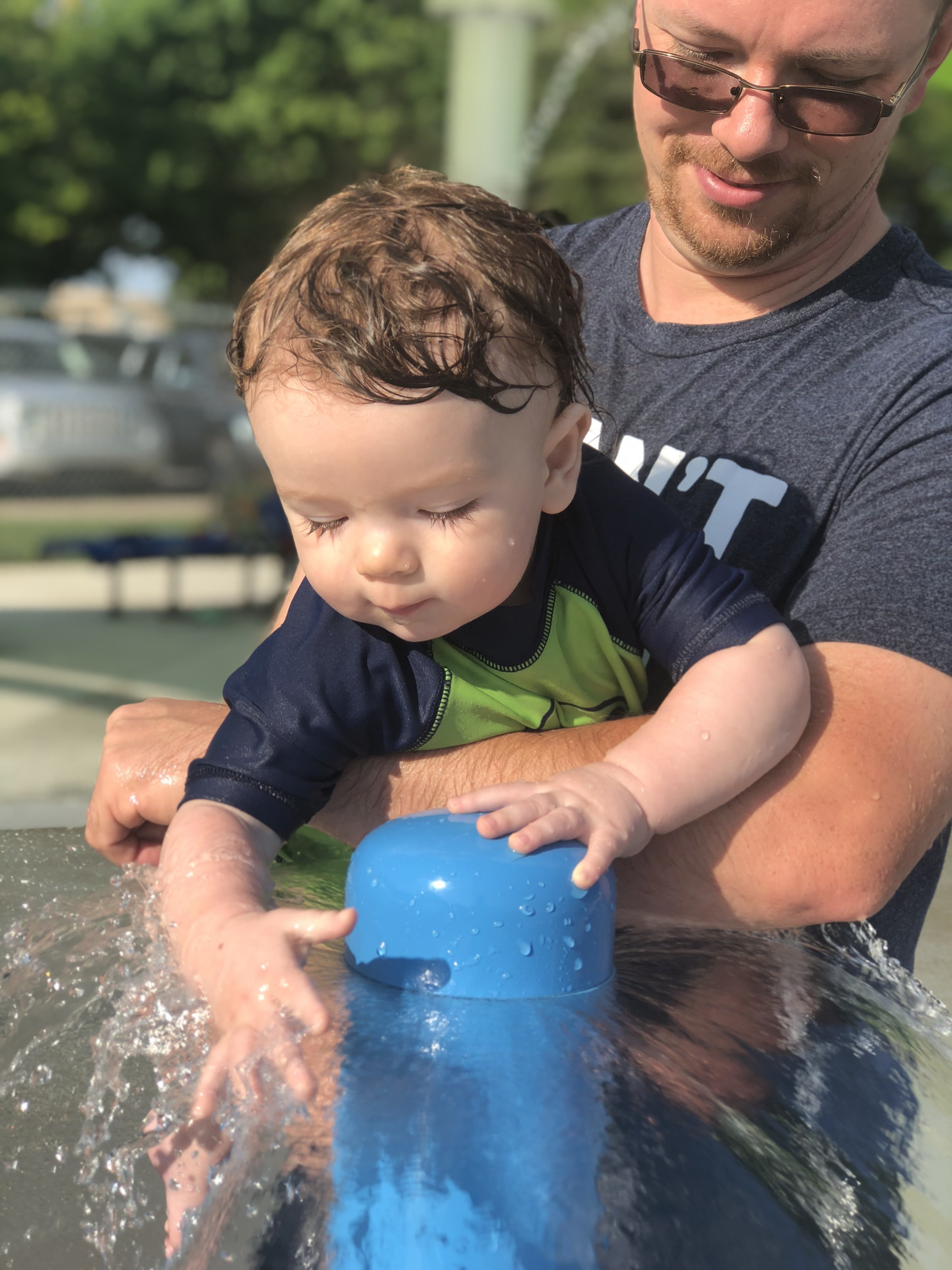 9 month old Shiloh running his hands in the umbrella sprinkler waterfall