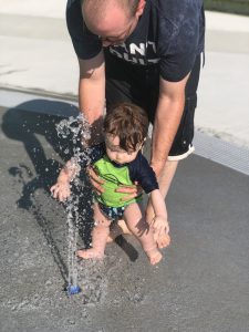 9 month old Shiloh running his hands in the umbrella sprinkler waterfall