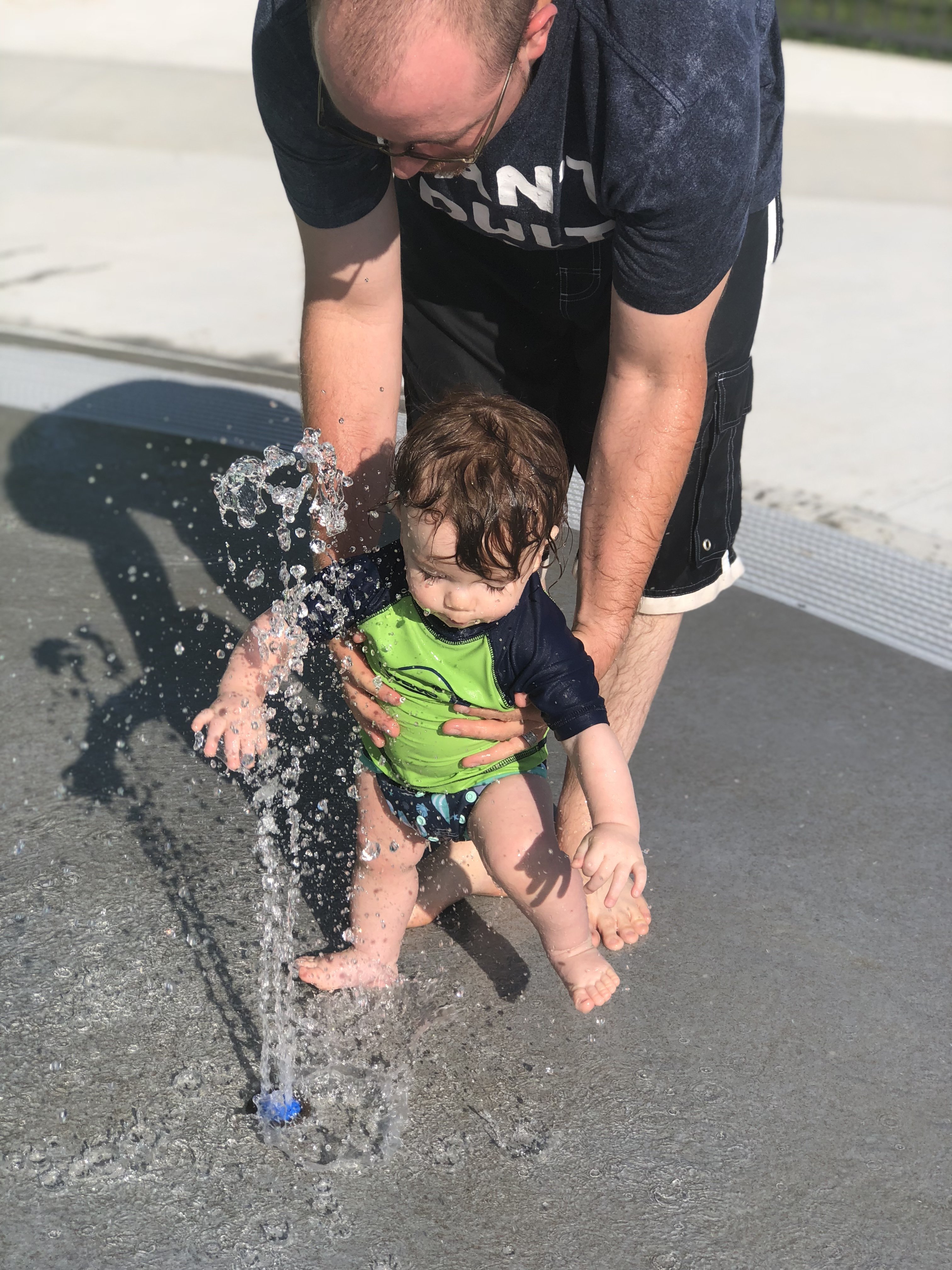 9 month old Shiloh running his hands in the umbrella sprinkler waterfall