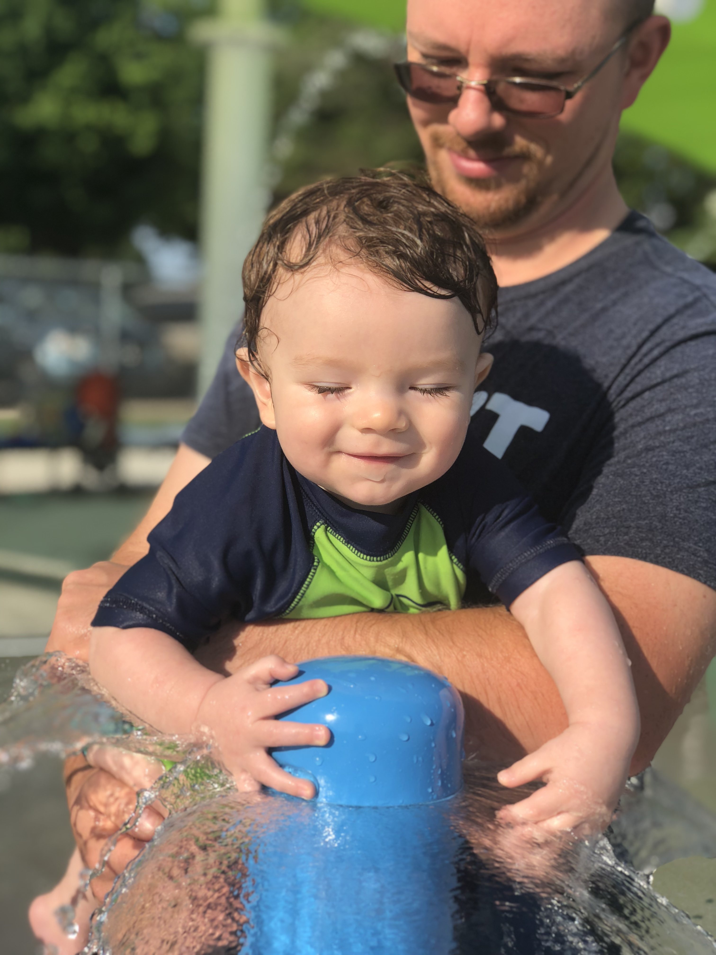 9 month old Shiloh running his hands in the umbrella sprinkler waterfall
