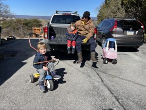 Matt (dad) with Shiloh on the truck tailgate and Asher peddling a toddler bike
